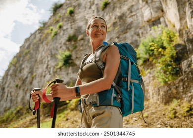 A Happy Woman Enjoying Hiking with Her Backpack and Trekking Poles Amidst Scenic Nature - Powered by Shutterstock