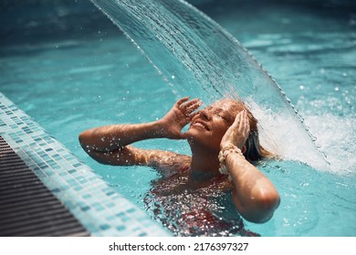 Happy woman enjoying in hydrotherapy in the swimming pool on summer day. - Powered by Shutterstock