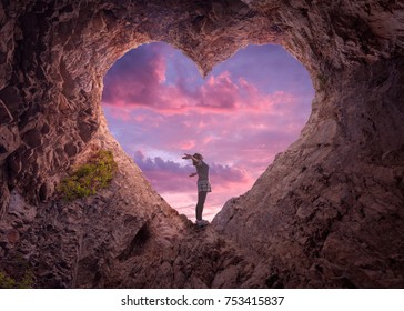 Happy woman enjoying in idyllic mountain nature, celebrating freedom and rising her arms while standing toward the setting sun. Valentines day concept.