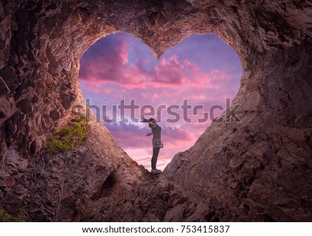 Happy woman enjoying in idyllic mountain nature, celebrating freedom and rising her arms while standing toward the setting sun. Valentines day concept.