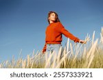 Happy woman enjoying nature outdoors in tall grass. Flying hairs. Outdoor. Fashion style.