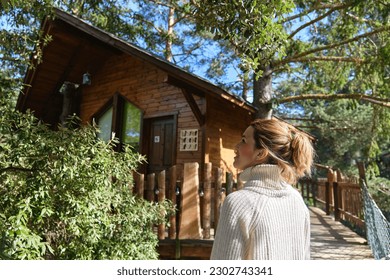 happy woman enjoying nature in a treehouse in the middle of the forest