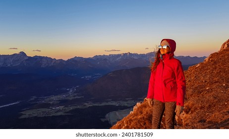 Happy woman enjoying scenic view during sunrise from Dobratsch, Villacher Alps, Carinthia, Austria, Europe. Looking at mountain ranges Julian Alps and Karawanks. Sunbeams reflecting in sunglasses. - Powered by Shutterstock