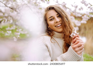 Happy woman enjoying scent in blooming spring garden. The concept of youth, love, fashion, tourism and lifestyle. - Powered by Shutterstock