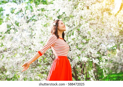 Happy Woman Enjoying Smell Flowers Over Spring Garden Background