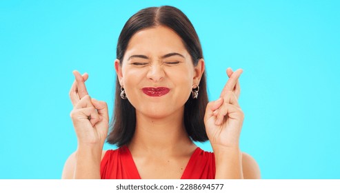 Happy, woman and face with fingers crossed on blue background, studio and wishing for good luck. Portrait of excited female model hope for winning prize, optimism and smile for emoji, hands and sign - Shutterstock ID 2288694577