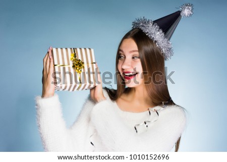 happy woman in a festive cap holding a gift on a blue background