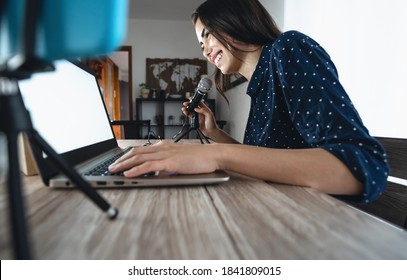 Happy woman filming video podcast with smart phone camera while using computer - Young girl having fun in live streaming on social networks - Youth people lifestyle and technology concept - Powered by Shutterstock