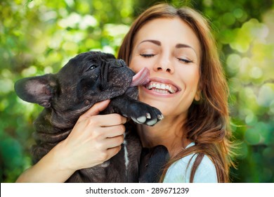 Happy woman with french bulldog on blurred nature background