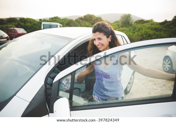 Happy woman getting\
into car at the coast