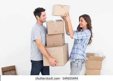 Happy woman giving boxes to her husband while they are moving