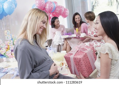 Happy woman giving a gift to an expecting mother at baby shower - Powered by Shutterstock