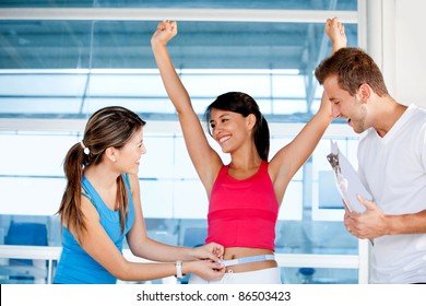 Happy woman at the gym with her trainers measuring her body ? weight loss