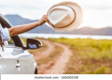 Happy woman hand holding hat outside open window car with meadow and mountain lake background. People lifestyle relaxing as traveler on road trip in holiday vacation. Transportation and travel concept - Powered by Shutterstock