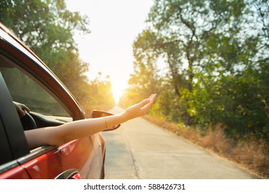 Happy woman hand out window car red with sunlight