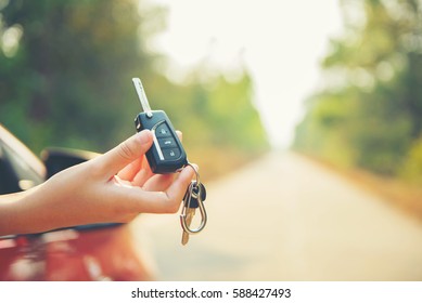Happy woman hand out window car red and car key with sunlight