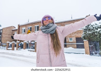 Happy woman with hands outstretched to the sides enjoying snowy winter outdoor. High quality photo - Shutterstock ID 2256252911