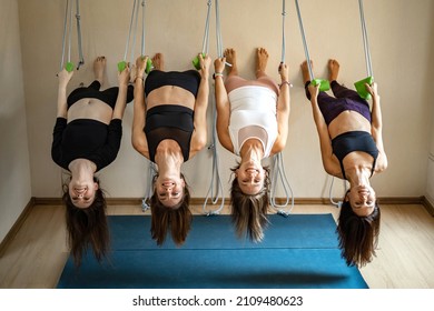 Happy woman hanged on rope legs near wall performing fly aero yoga Iyengar posture at gym class. Smiling athletic female practicing deflection in thoracic flexibility body harmony balance activity