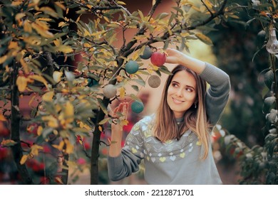 
Happy Woman Hanging Lighting Decorations In Her Garden. Cheerful Party Host Decorating Backyard For The Holidays
