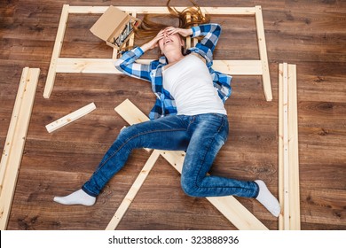 Happy Woman Having Fun Assembling Furniture At Home. Young Girl Laying On Floor Arranging Apartment House Interior. DIY. High Angle View.