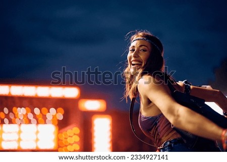 Happy woman having fun while attending open air music concert at night and looking at camera. 