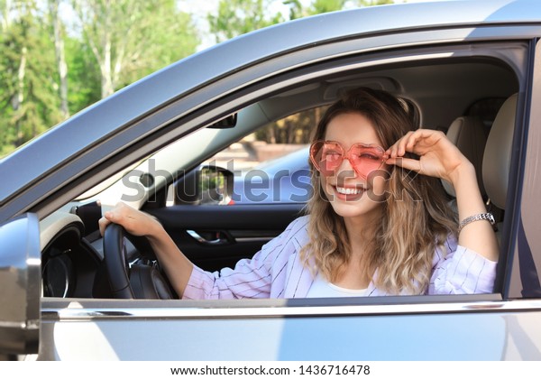 Happy woman with\
heart shaped glasses in\
car