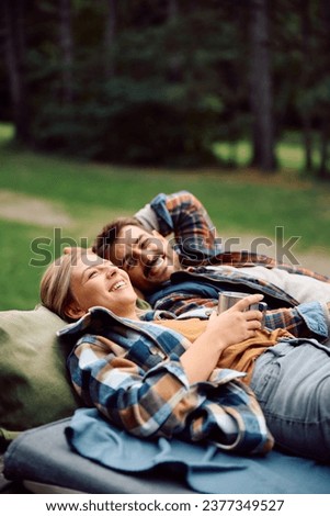 Happy woman and her boyfriend enjoying while lying down on top of their camper trailer in nature. Copy space.