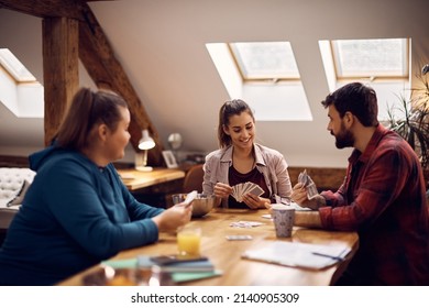 Happy Woman And Her College Friends Playing Poker With Cards In Common Living Room. 