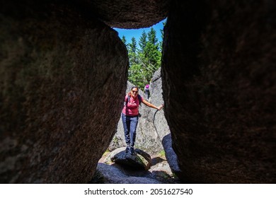 Happy Woman Hiker Portrait , View Through Rocks Formation. Summer Day. Adventure In Nature.