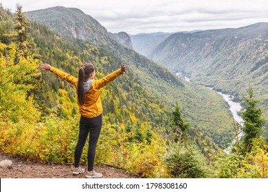 Happy Woman Hiking Up Mountain Enjoying Nature. Landscape With River View From Top Of Trail Hike. Girl With Open Arms Outstretched In Joy, Enjoying Travel Fall In Jacques Cartier, Quebec, Canada. 