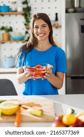 Happy Woman Holding Bowl Of Salad And Looking At Camera.