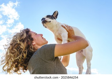 Happy Woman Holding Up A Bulldog. Horizontal View Of Woman With Pet Outdoors. Lifestyle With Animals