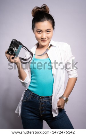 Happy woman holding camera over background and looking at camera