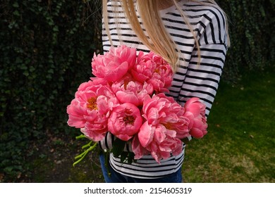 Happy woman holding pink peonies in her hands. The florist girl collected a bouquet of peonies. Delicate flowers are beautiful. A gift for the holiday, spring mood. romantic surprise