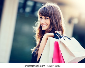 Happy woman holding shopping bags and smiling at the mall