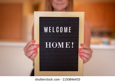 Happy Woman Holding Welcome Home Sign