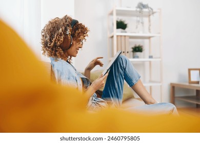 Happy Woman at Home: Relaxing with Music and Games on Tablet PC while Sitting on Cozy Couch in Living Room - Powered by Shutterstock