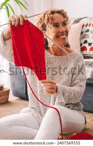 Happy woman at home show her knit work results. Laptop on the carpet. Online hobby internet leisure activity people. Adult female enjoying time indoor. Knitting working cheerful lady concept lifestyle
