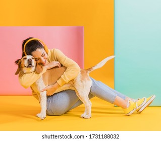 Happy woman hugging a cute dog. Colorful creative yellow studio background. - Shutterstock ID 1731188032