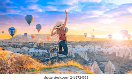 Happy woman jumping in air- beautiful sunrise Cappadocia landscape with hot air balloons flying in the sky - Powered by Shutterstock