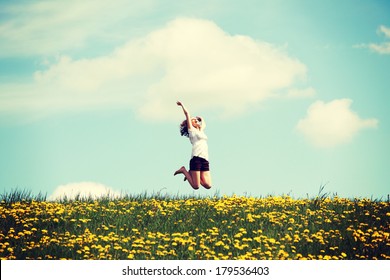 Happy woman jumping on blossom meadow. Beautiful day on field.