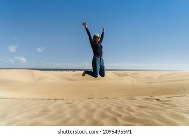 Happy woman jumps on the dunes in Maspalomas Nature Reserve, Gran Canaria, Canary Islands, Spain - Powered by Shutterstock