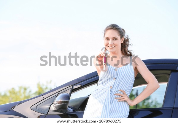 Happy woman with key\
near new car outdoors