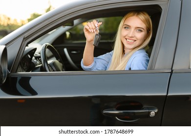 Happy woman with keys in car, driving school