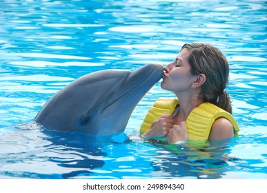 Happy Woman Kissing Dolphin In Pool