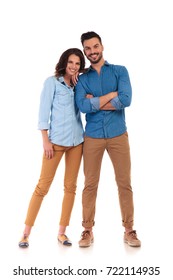 happy woman leaning on her man's shoulder; young casual couple smiling on white background, full body picture