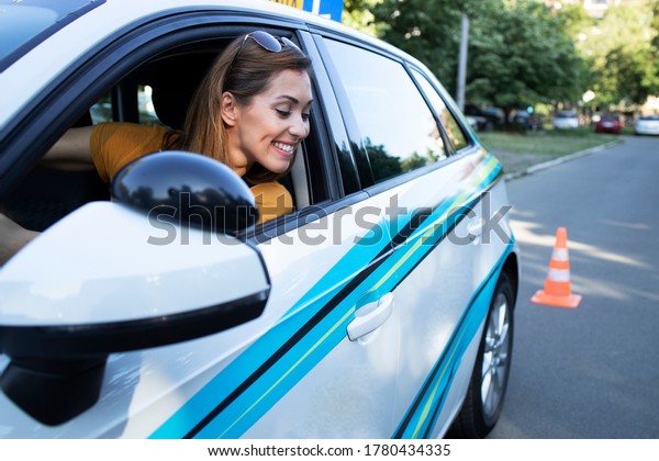 Happy woman learning to drive a car and\
going reverse. Car driving school and\
lessons.