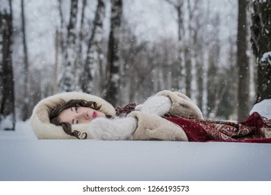 Happy woman lie around in soft snow on a winter day, rejoicing the snowfall. - Powered by Shutterstock