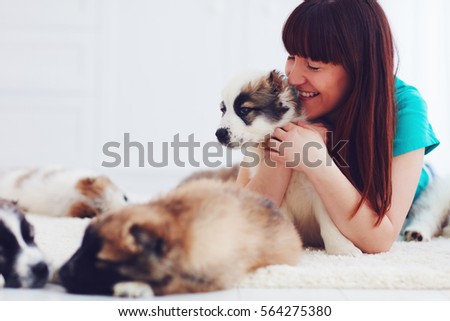 happy woman lies on carpet with caucasian shepherd puppies