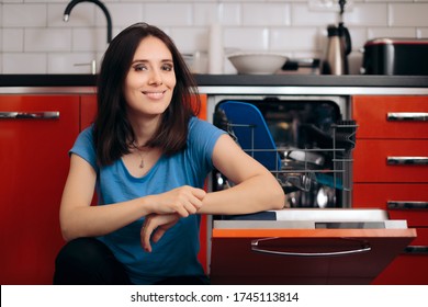 Happy Woman Loading The Dishes In Dishwashing Machine. Woman Using Electric Washer For Household Chores
